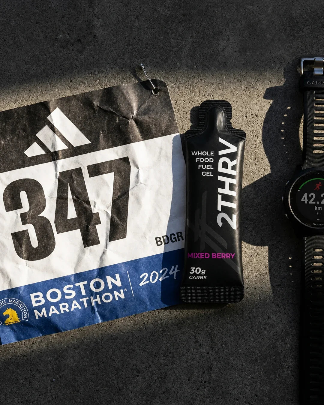 Marathon race bib, sports watch and 2THRV endurance fuel
