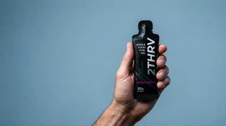 Hand holding a 2THRV whole-food energy gel in the studio